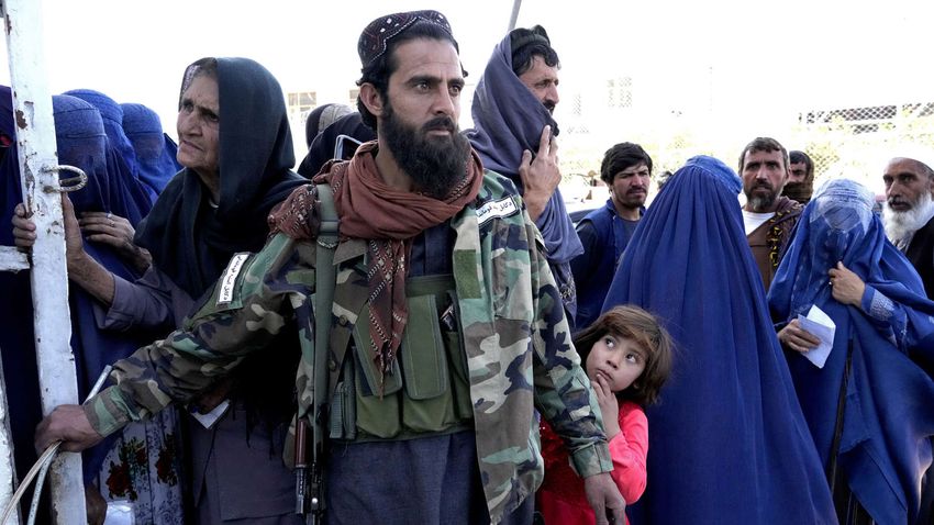 Střelec z Talibanu stojí na stráži u lidí stojících ve frontě na jídlo v dubnu 2022